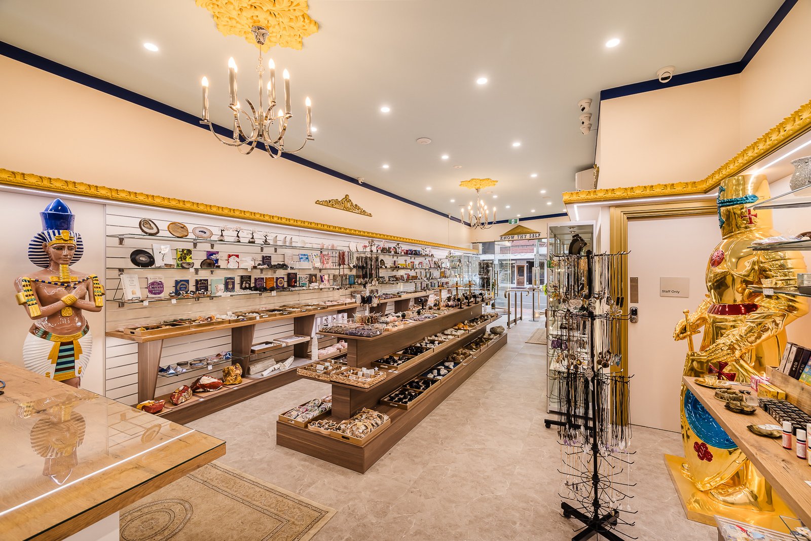 Inside Atlantis Centre Crystal Gift Shop, with crystals, books and jewellery beneath chandeliers and gold-trimmed displays